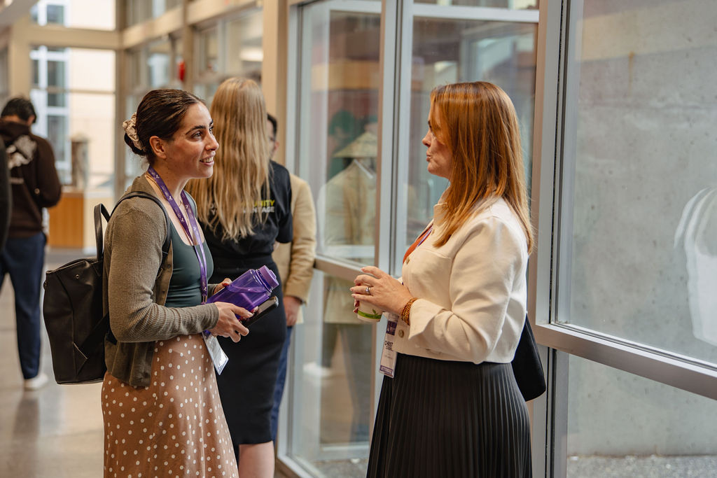 Two attendees having a conversation beside the windows